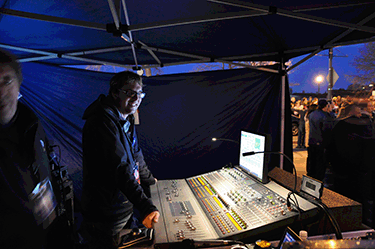 Gregory Rushton stands in front of an audio console in a tent