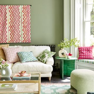 Green living room with pink patterned fabric wall hanging