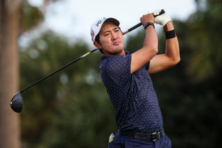 Takumi Kanaya watches his tee shot with a driver