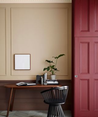 beige panelled wall with dark red wall, wooden desk, black modern chair