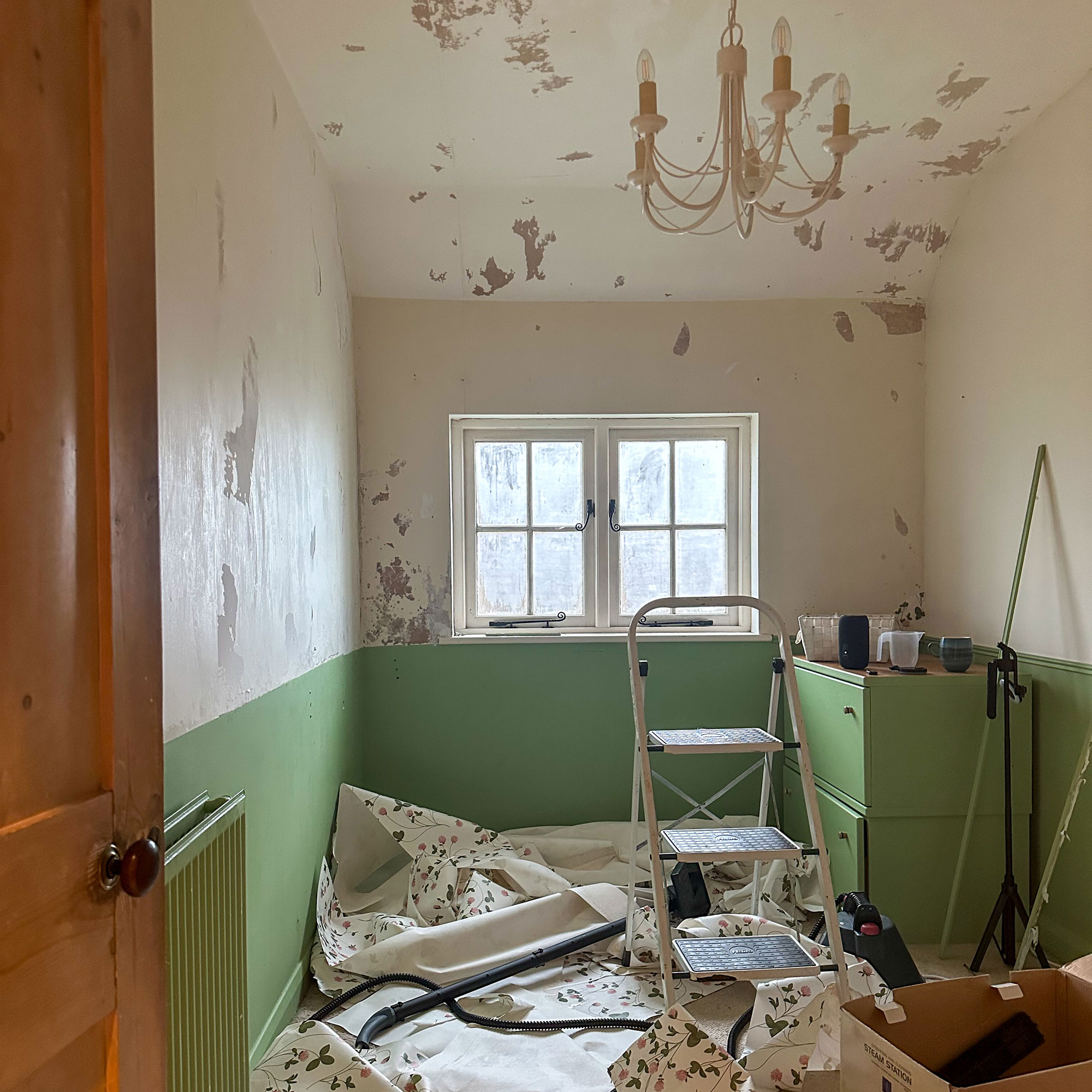 Small box room mid-renovation with white and green painted walls, white chandelier and stepladder
