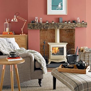 A terracotta red living room wall by a fireplace with cream log burner