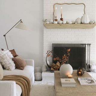 A fireplace mantel decorated with white pumpkins