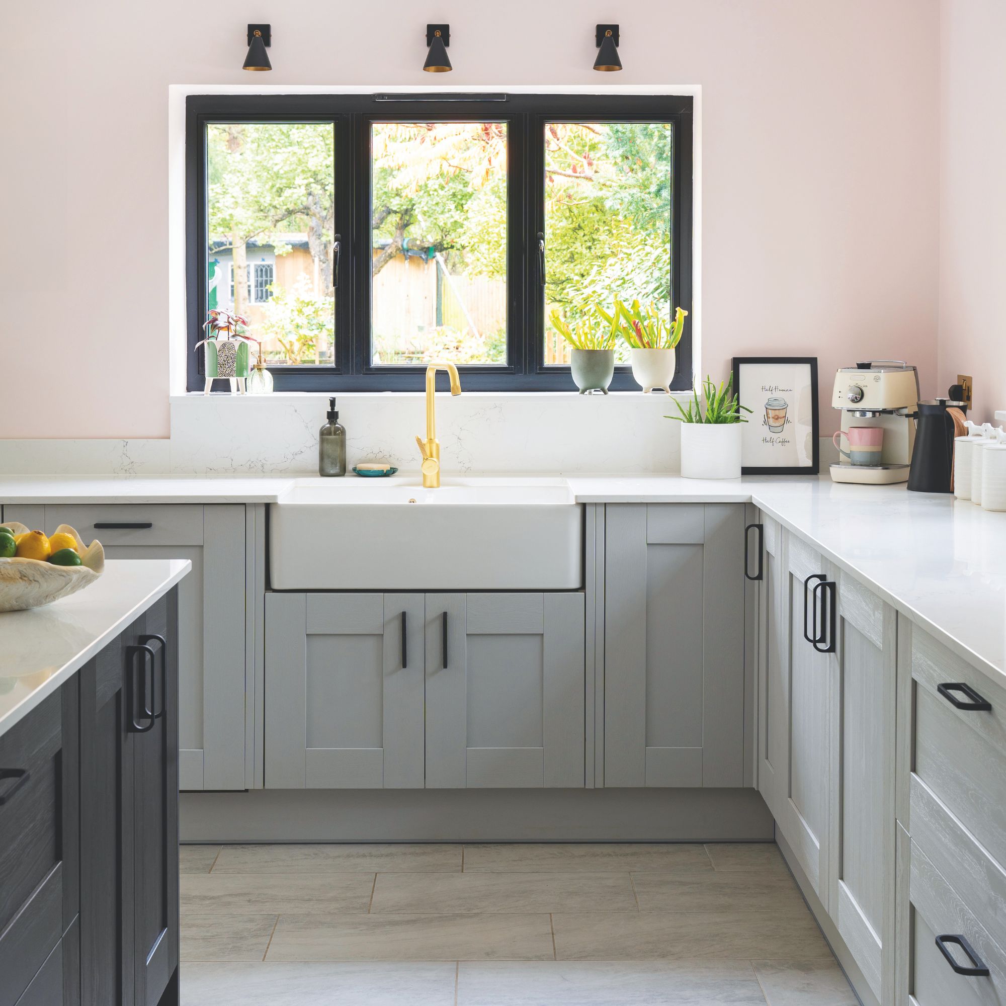 Pink painted kitchen with grey cabinets and a white ceramic sink