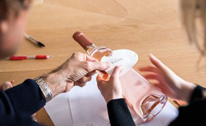 La Bastide Peyrassol rose wine bottle being held by one person with another person holding the wine label over the bottle