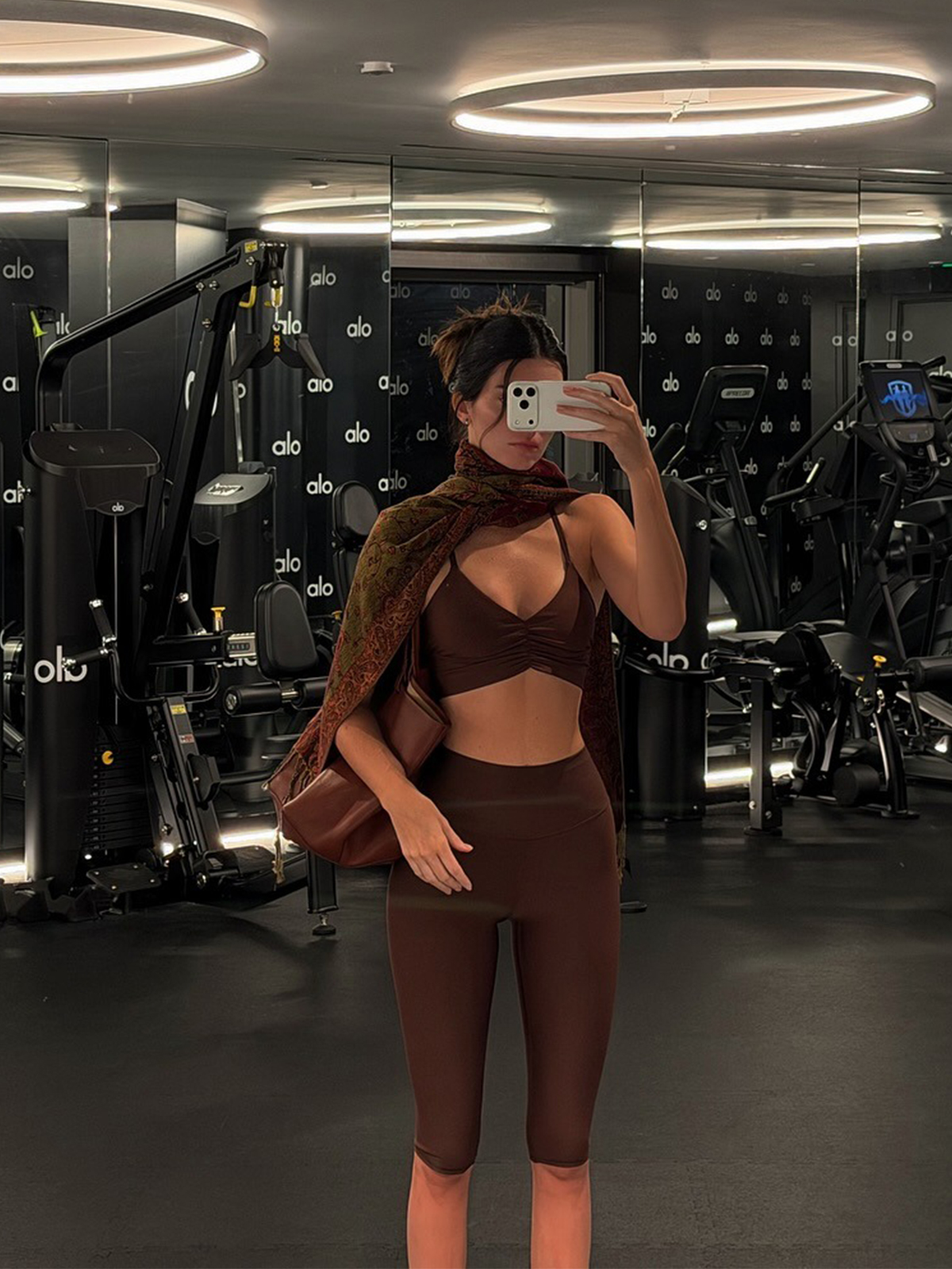 Kendall Jenner at the Alo gym wearing a brown sports bra and matching capri pants.