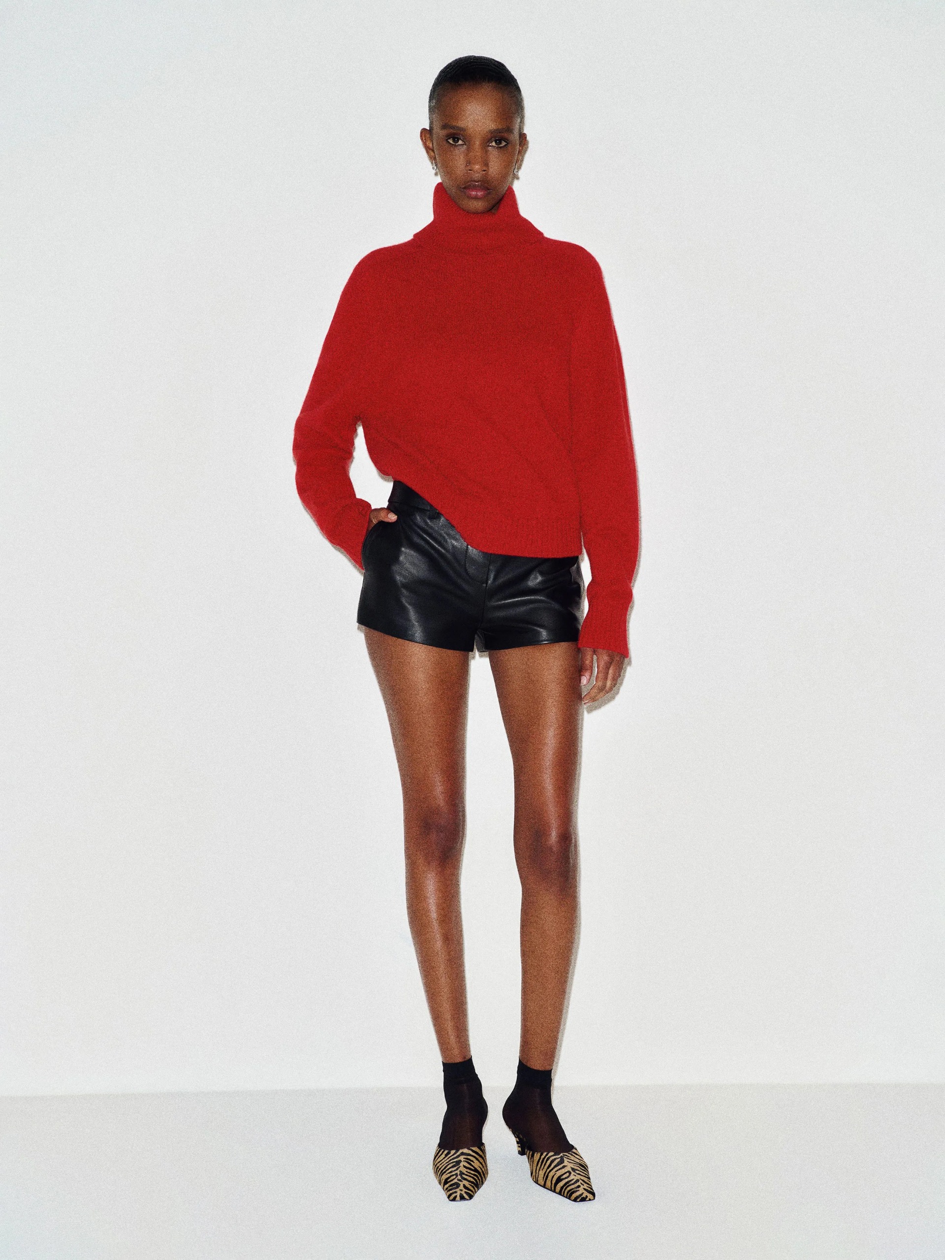 A model wearing a bright red turtleneck jumper from Reformation