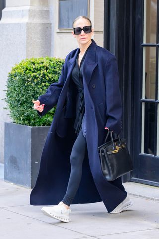 J.Lo wears a navy jacket, navy leggings, and white sneakers