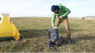 how to use a dry bag: man packing backpack