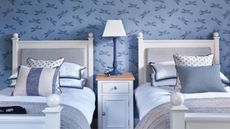 A childrens bedroom with twin beds and blue wallpaper