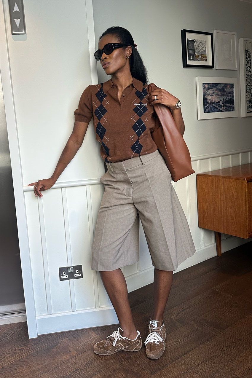 A woman wearing a brown knit polo, tan culottes, and suede brown sneakers