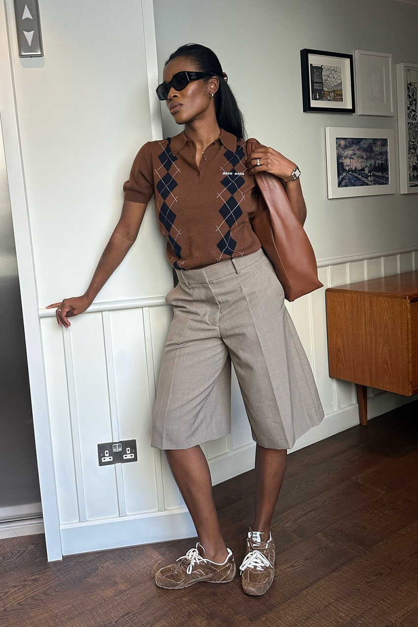 A woman wearing a brown knit polo, tan culottes, and suede brown sneakers