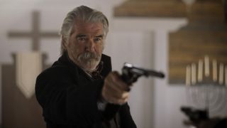 Pierce Brosnan pointing a gun in The Unholy Trinity