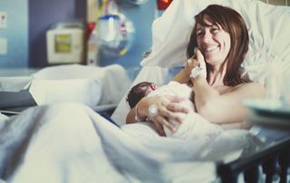 Smiling woman with her newborn in a hospital bed