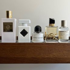 A wooden shelf with perfumes perched on top, from brands including Byredo and YSL