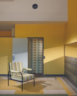 A 1970s style room with green and yellow geometric patterned walls, rug and chair