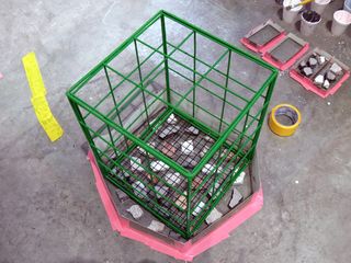 Wire crate, pieces of concrete, yellow and pink tape