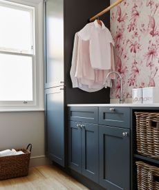 dark blue utility space with pink floral wallpaper and wooden clothes rail
