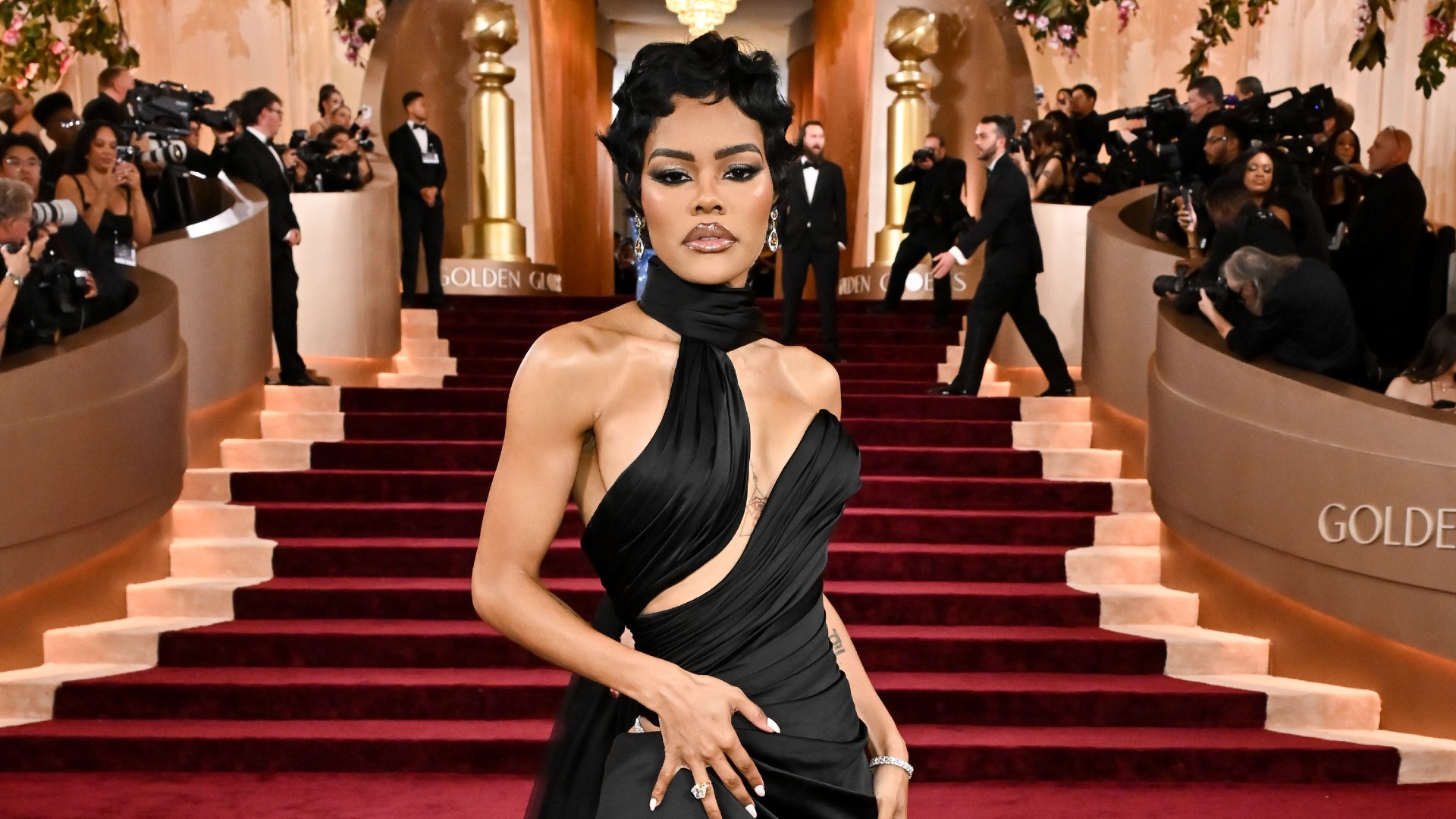 a black woman with short hair posing on a red carpet wearing a black gown