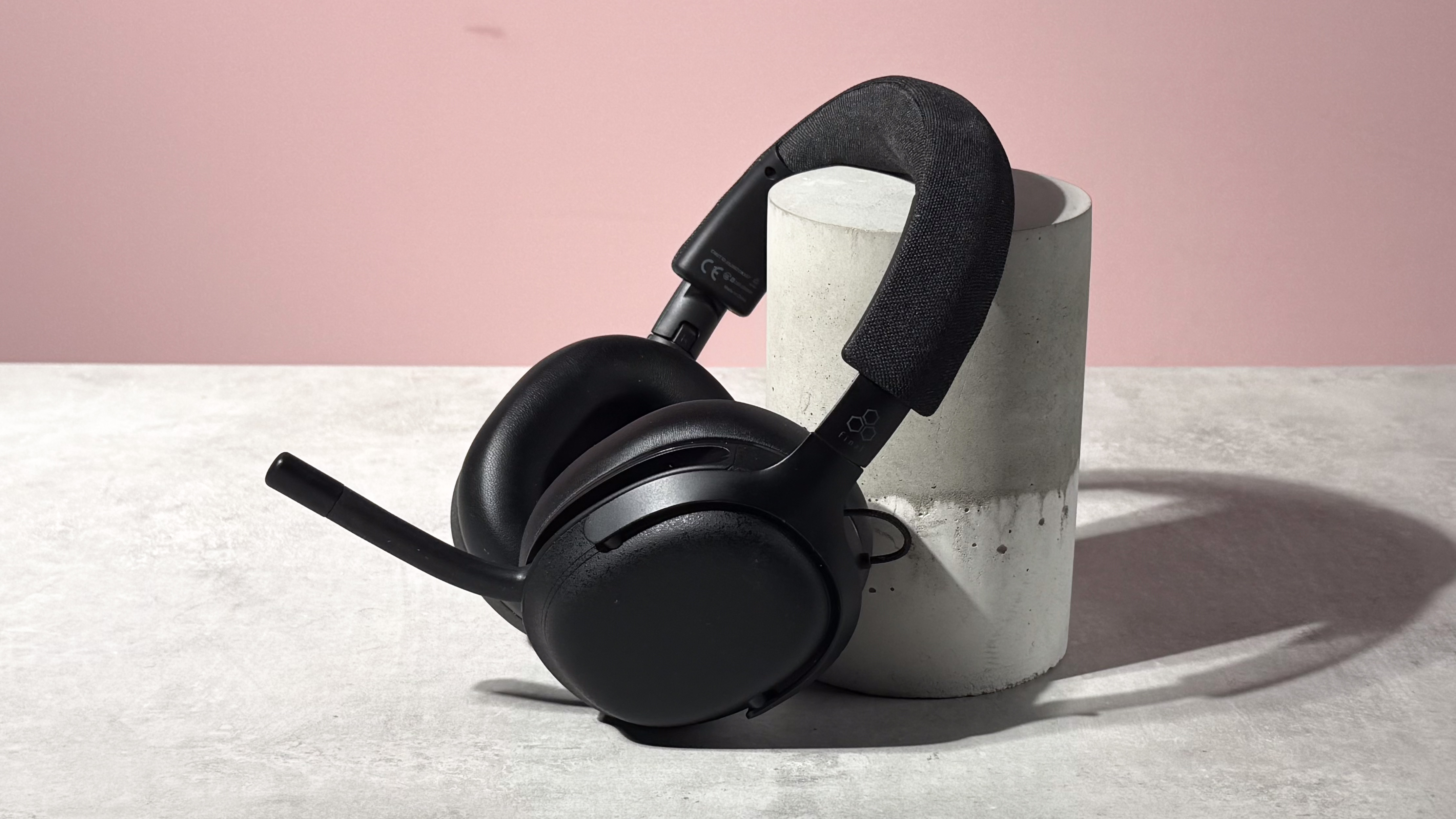 The Final VR3000 EX for Gaming with the mic unfolded leant at a 45 degree angle against a stone and concrete cylinder.