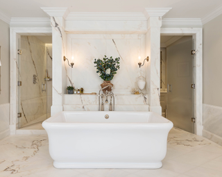 bathroom with white roll top, marble flooring, glass doors, marble wall, neutral scheme