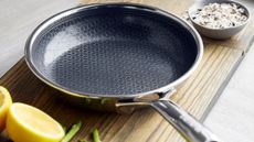 GreenPan Spectra Thermobond Frying Pan on a wooden cutting board, with some halved lemons beside it. 