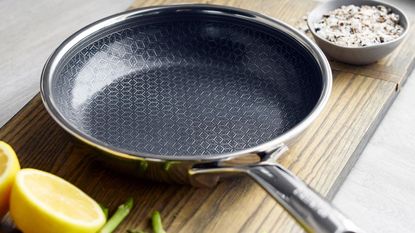 GreenPan Spectra Thermobond Frying Pan on a wooden cutting board, with some halved lemons beside it. 
