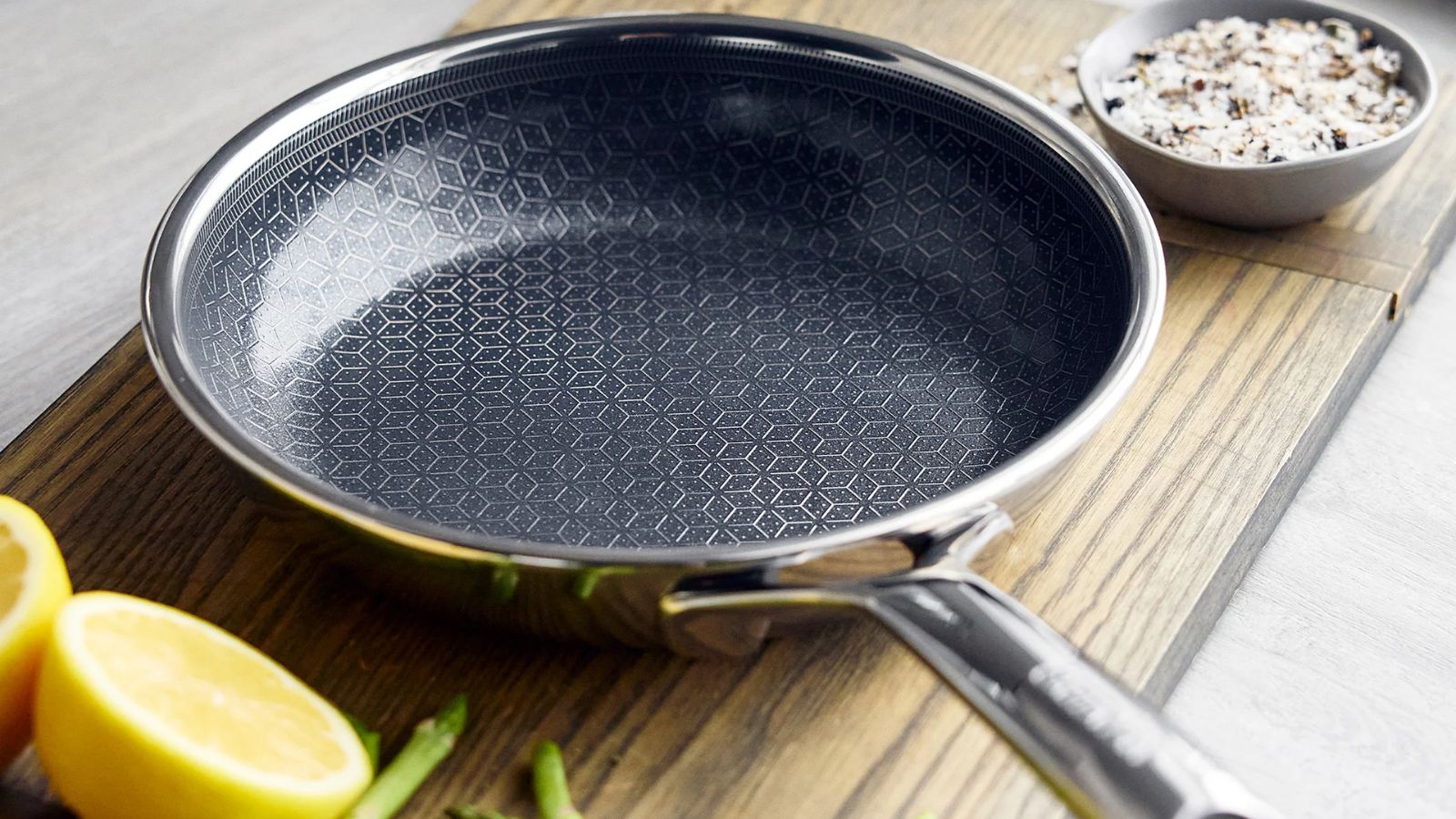 GreenPan Spectra Thermobond Frying Pan on a wooden cutting board, with some halved lemons beside it. 