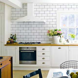 Wooden and white kitchen with built-in oven and gas hob with cooker hood