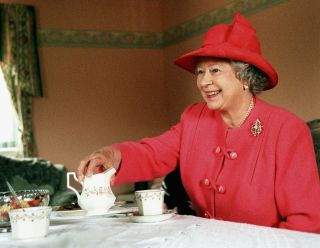 The Queen sweet snack GLASGOW - JULY 7: Queen Elizabeth II joins Mrs Susan McCarron, her ten-year-old son, James, and Housing Manager Liz McGinniss for tea in their home in the Castlemilk area of Glasgow in Scotland on July 7, 1999. (Photo by Anwar Hussein/Getty Images)