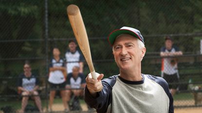 A retiree smiles as he warms up his softball swing.