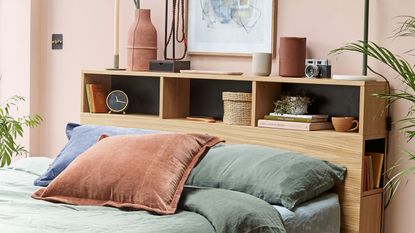 Bed with wooden storage headboard holding books, clock and vases