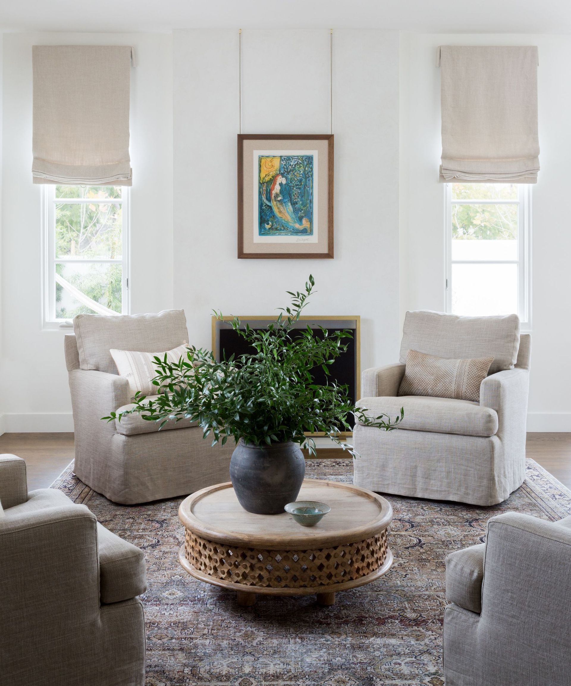 living room with white walls four armchairs vintage rug and round coffee table