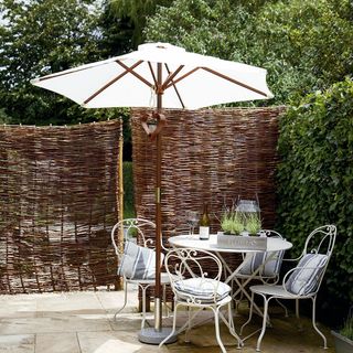 garden area with willow fence and patio table under umbrella