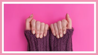 woman's hands showing off Christmas nails—a snowflake manicure on pink nails, against a pink background