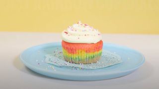 rainbow cupcake with buttercream frosting on a plate
