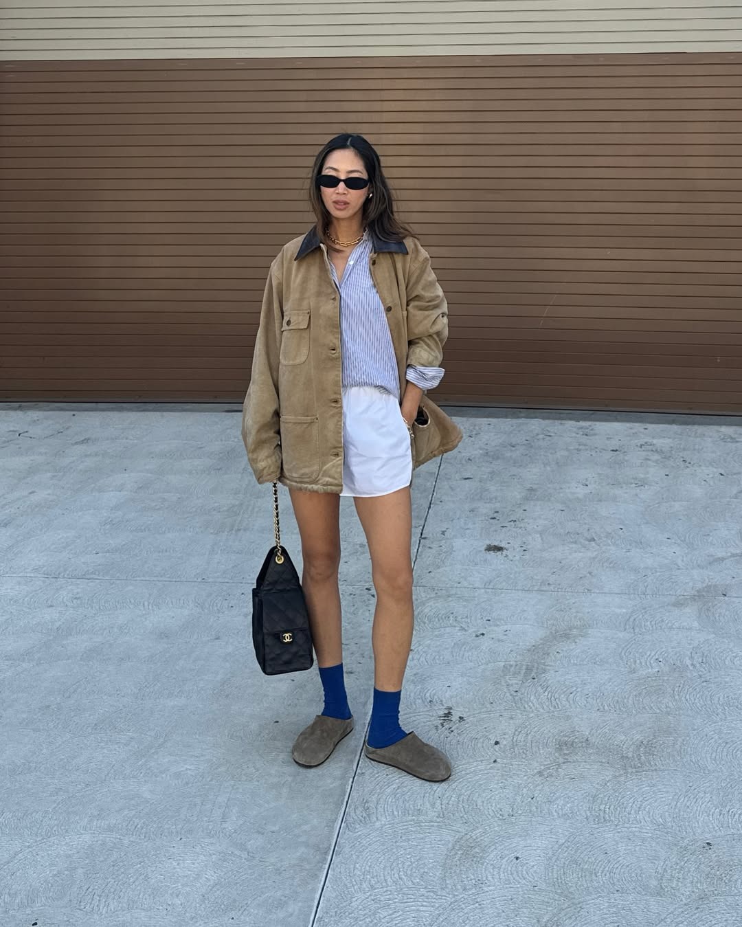 Woman in slip on mules, shorts, and a barn jacket