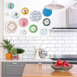 white tiled kitchen with an array of plates on the wall
