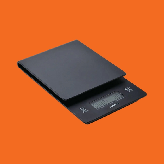 A black coffee scale in black with a geometric design sits diagonally against a bright orange background.