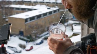 Man using a straw to blow a bubble using a frozen bubble solution