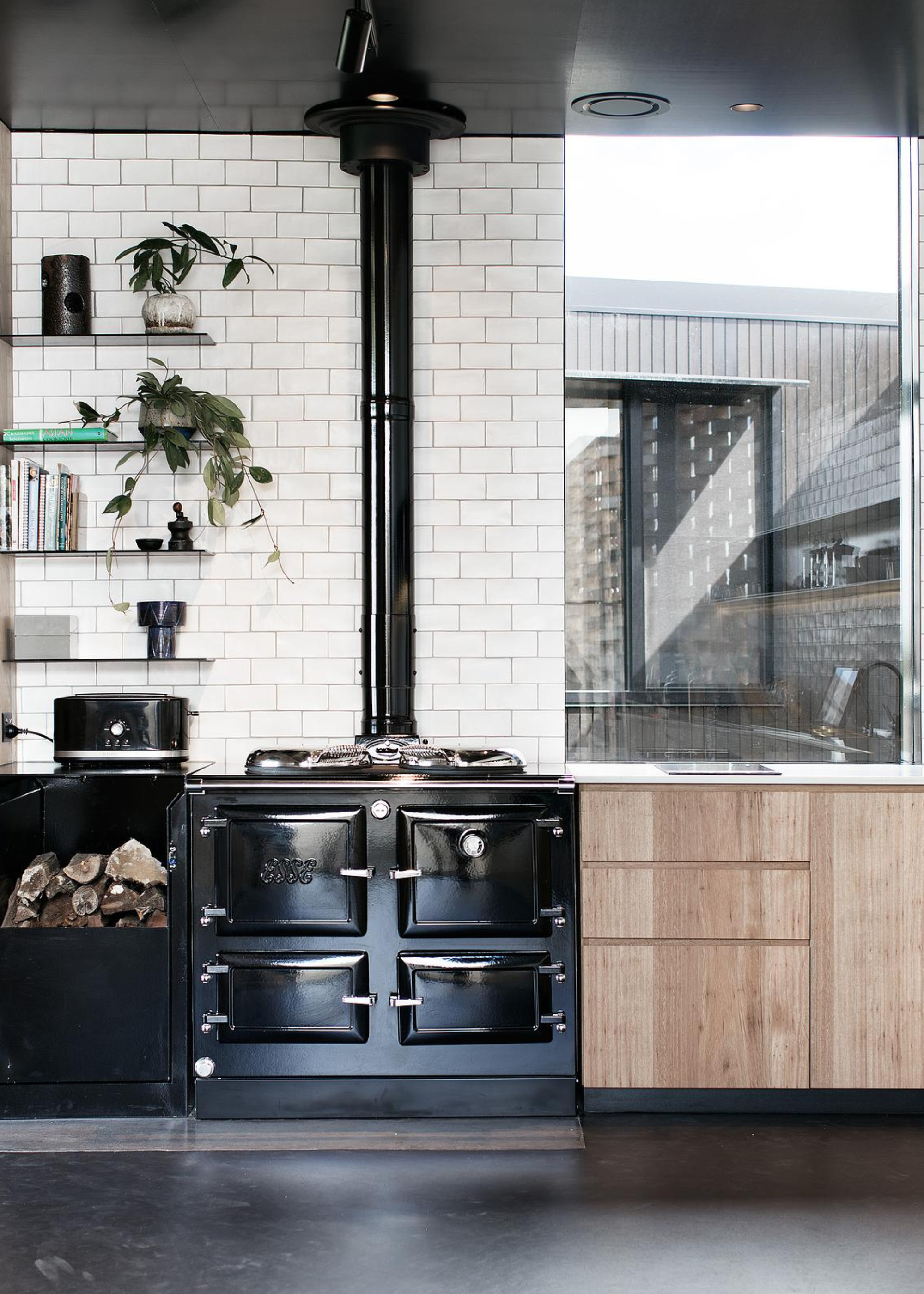 a modern aga kitchen with a black range cooker against white subway tiles and wood cabinets