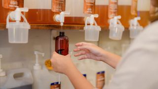 picture of woman using a refillable station with a glass bottle