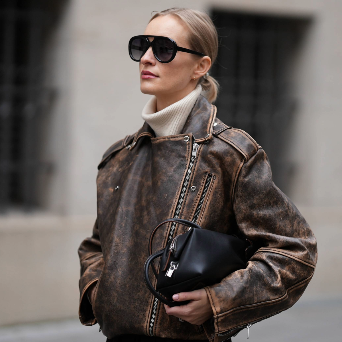 MUNICH, GERMANY - NOVEMBER 7:Marlies Pia Pfeifenhofer is seen wearing a distressed brown leather biker jacket with a stand-up collar and asymmetrical zip-up front by H&M Studio; a beige cashmere turtleneck sweater by Allude; a structured black leather baguette bag with long handles and brown accent details by Max Mara; oversized aviator sunglasses with a double-bridge frame by Kaleos; her blonde hair is styled in a sleek low bun on November 7, 2025 in Munich, Germany. (Photo by Moritz Scholz/Getty Images)