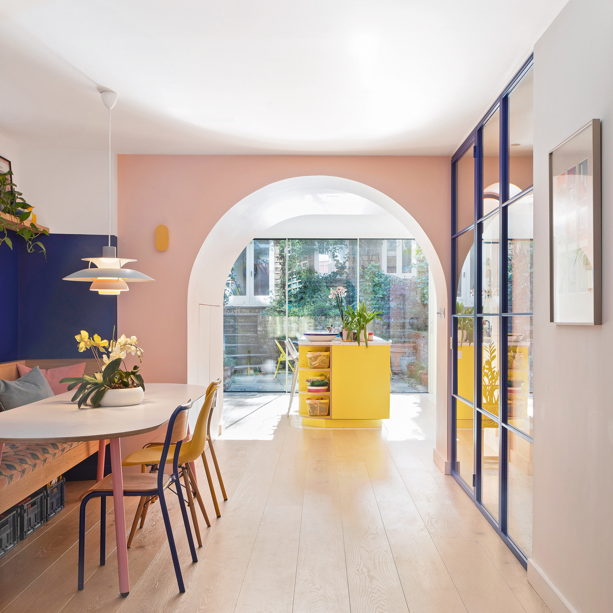 kitchen with a yellow island, pink walls and a open plan dining area