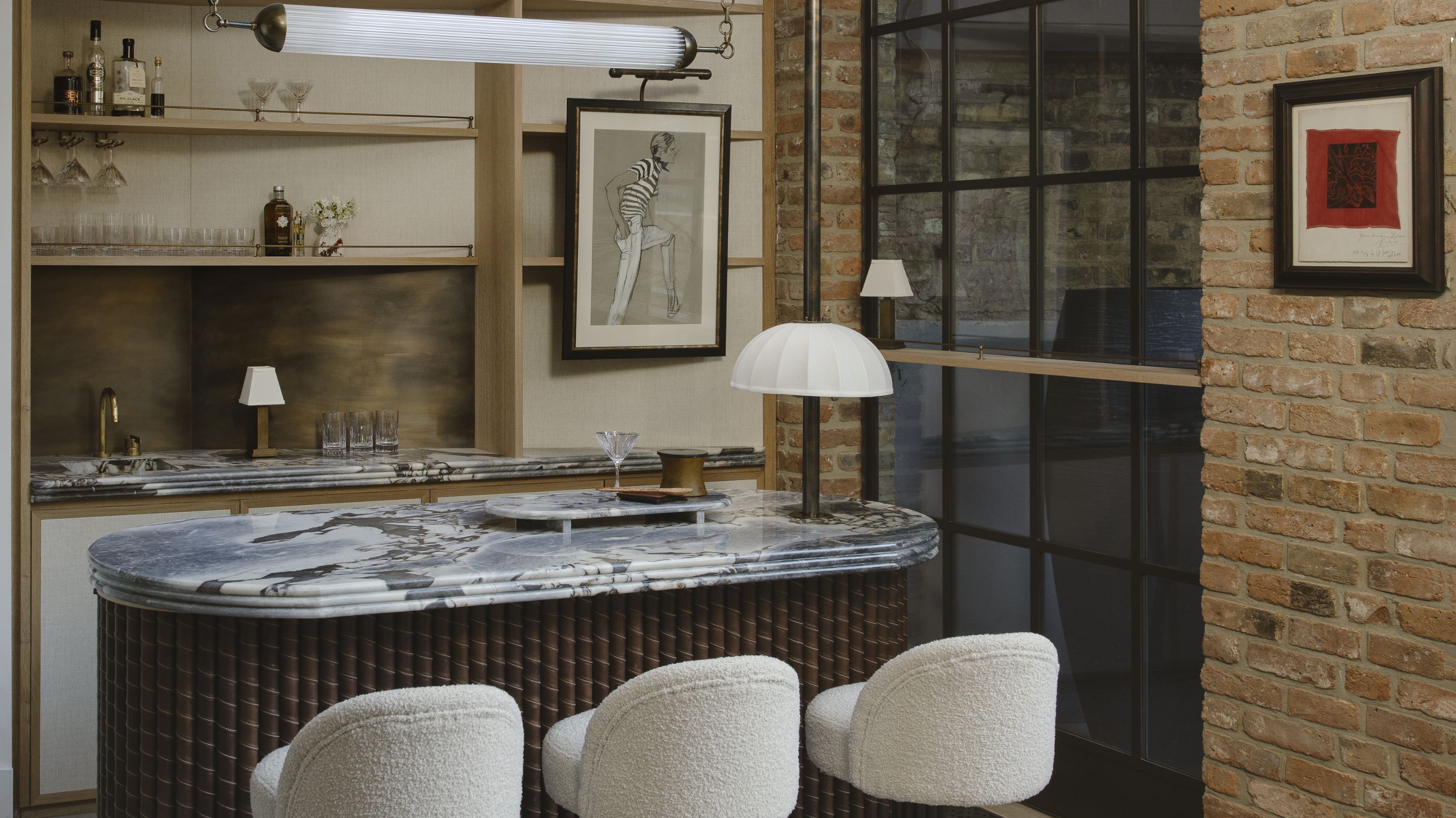 An indoor-outdoor home bar, with a marble counter, bar chairs, and a horizontal tube light 