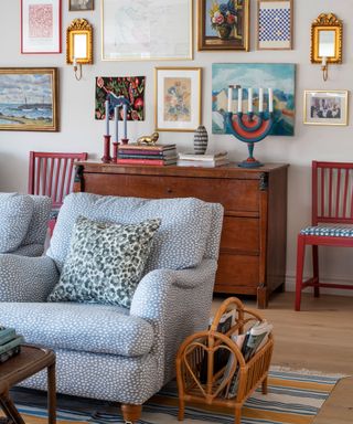 eclectic vintage living room with two blue armchairs and a galley wall with antique furniture