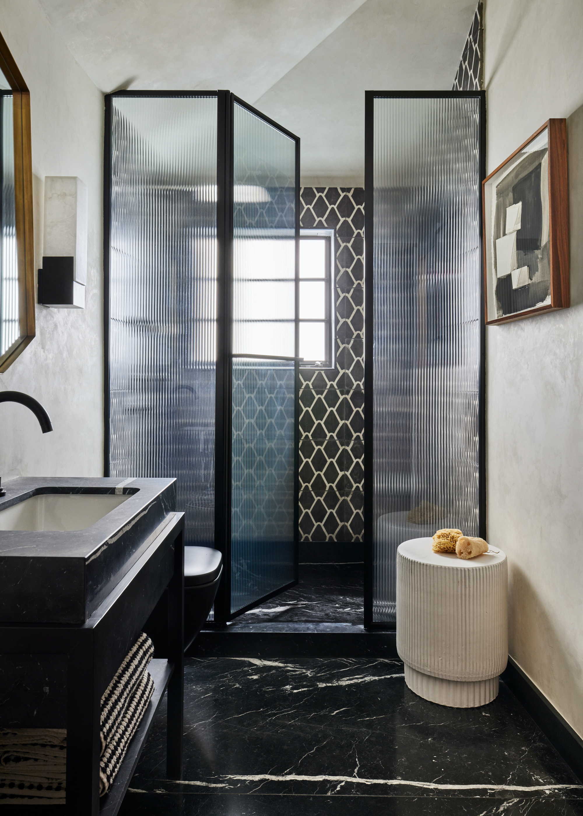 shower with black framed enclosure and black marble floors and monochrome tiles on the wall
