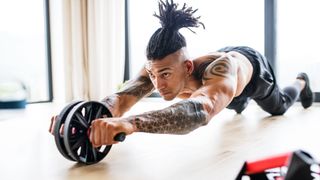 Man using abs wheel to perform abs roll-out core exercise
