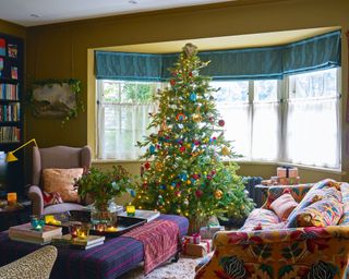 Colorful, patterned living room with green walls, bay window and Christmas tree