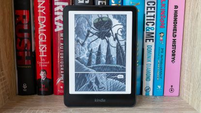 Kindle Colorsoft Signature Edition in front of books (and showing coming book page)